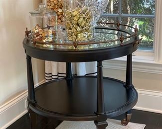 Drexel Heritage side table with smokey glass top and brass rail. On casters. Measures 31" D x 30" H.