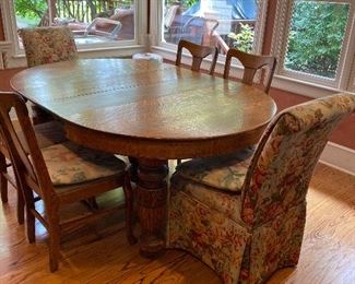 SOLID TIGER OAK TABLE W/4 OAK CHAIRS AND 2 FLORAL PARSONS CHAIRS. TABLE IS ROUND W/O LEAVES(3) AND ORNATE LEGS