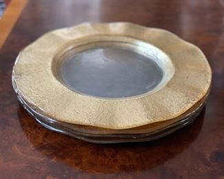 Set of four glass chargers with gold fluted rims.