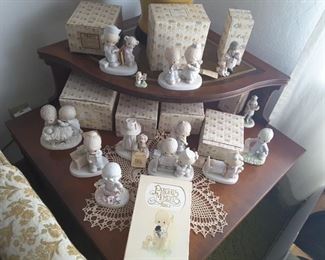 Precious Moments Collectibles with matching boxes. Precious Moments Bible.  Hand crocheted beige Doilie.. Vintage Wood Corner End Table with 2 Shelves. Tall Table Lamp in the back.