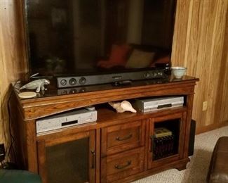 Beautiful oak cabinet. VIZIO 55" smart TV, LG sound bar, and two VHS/DVD players.