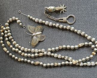 Two strings of sterling silver beads, a butterfly and key chain with spur (and horsehead that is unseen at this angle.)