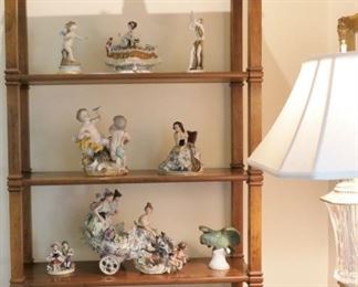 Selection of European porcelain figurines. Waterford floor lamp shown at right edge of photo. Display shelf is mid century (early 1960s)