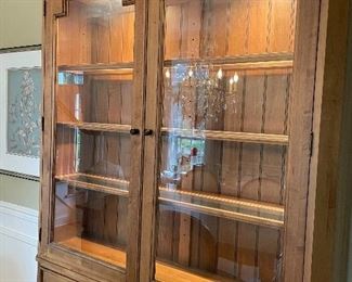 Ethan Allen Spencer Cabinet with a Mushroom hue finish. This inspired display cabinet features glass door panels, glass shelving and halogen canister lighting. The base of the unit has two drawers and two cabinets with shelving.  51.5" W x 20" D x 86" H