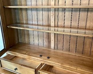 Ethan Allen Spencer Cabinet with a Mushroom hue finish. This inspired display cabinet features glass door panels, glass shelving and halogen canister lighting. The base of the unit has two drawers and two cabinets with shelving.  51.5" W x 20" D x 86" H