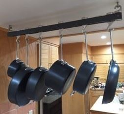 A series of skillets and pans of different sizes hang from a rack.