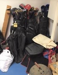 Two sets of golf clubs and bags lean against the back wall.  There is a basic grill in the foreground.