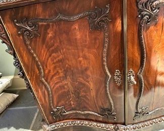 A Pair of GEORGE II Style Mahogany Commodes ~~Late 19th Century  Each with serpentine top above a pair of cartouche paneled cupboard doors, moldings and floral clasps to the corners enclosing a silk-lined interior plinth base.  Purchased at CHRISTIES