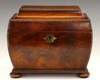 Lot 28: An early 19th century British Regency Period tea caddy.  Figured Mahogany case in sarcophagus form with beaded edge detail, Brass escutcheon and flattened ball feet.  Opens to reveal two foil lined tea compartments.  Polished finish with minor wear, slight veneer lifting.  8 x 5 x 6 3/4" high overall.  ESTIMATE $600-800