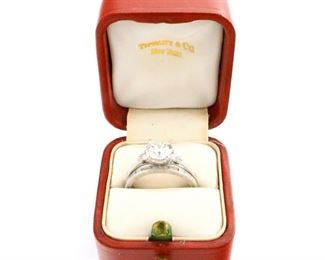 Lot 45: An Art Deco era Platinum and Diamond wedding set.  Includes a Tiffany & Co. engagement ring consisting of 1 center round brilliant cut diamond, approximately 1.25 cts, flanked by two trillion cut diamond accents, approximately 0.25 cttw, with a matching wedding band consisting of 25 small diamond baguettes.  Engagement ring marked "Tiffany & Co." and "IRID PLAT", band unmarked but tested platinum.  5.4 grams total weight.  Both engraved, some wear and scratches, center diamond with tiny bowtie shaped chip near setting, in original box.  Size 6 1/4.  ESTIMATE $3,000-5,000