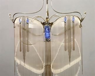 Lot 47: A 20th century French Nickel plated chandelier in the manner of Hector Guimard (French, 1867-1942).  Art Nouveau style cast foliate design with scroll frame, tendrils supporting clear glass rod-form prisms and Blue oval glass panels with four interior lights.  Very good condition with slight wear, two glass rods damaged.  38 x 18 x 48" high overall plus chain and canopy.  ESTIMATE $2,000-4,000