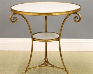 Lot 81: A 19th century French Bronze and Marble gueridon.  Circular White Marble top with a Gilded Bronze frame, three shaped legs with central Marble shelf and stretcher base with foliate finial and lower casters.  Some wear to Gilding.  27 1/2" diameter x 29 1/2" high overall.  ESTIMATE $2,000-3,000