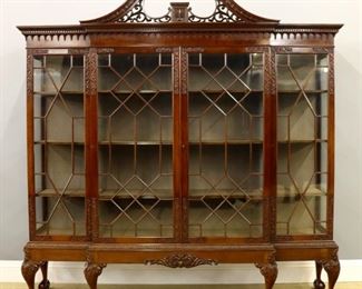Lot 92: A Good Quality early 20th century British Chippendale style breakfront display cabinet by "Robson & Sons Ltd., Newcastle-on-Tyne".  Mahogany construction features a Classical broken arch crown with pierced carved scroll work above a dentil molded crown with turned drops, over four glazed doors with geometric mullions and carved foliate corners, on a conforming base with shaped central skirt and carved foliate drop, tall cabriole legs, carved knees and bold ball and claw feet.  Interior with adjustable shelves and fabric lining.  The cabinet disassembles into several sections for moving.  Original finish with only minor wear, lacks several small turnings.  86 x 18 x 90 1/2" high overall.  ESTIMATE $6,000-8,000