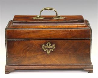 Lot 99: A late 18th century British George III Period tea caddy.  Figured Mahogany case in rectangular form with deeply molded top, Ebony stringing, Brass handles and escutcheon, and ogee bracket feet.  Opens to reveal three tea boxes with sliding paneled lids.  Older finish some wear and minor damage.  10 3/4 x 6 x 6 3/4" high overall.  ESTIMATE $600-800