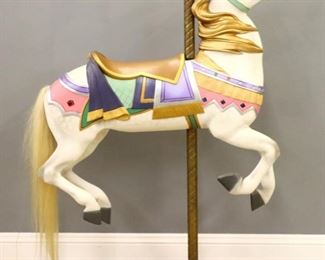 Lot 136: A turn of the century American carousel horse.  Carved wooden construction, second row jumper with multicolor painted design, carved saddle and breast collar, and inset jeweled detail.  Restored by Tony Orlando, on a modern Oak base with Brass stand.  Modern paint with some wear and shrinkage.  Approximately 47 x 12 x 65" high overall.  ESTIMATE $600-800