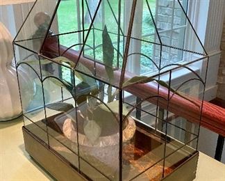 Lot 9041. $45.00. Cute Tabletop Vintage Greenhouse with leaded glass on little feet, 14.5" x 9.5" x 21" - Has faux plant in a stone pot in it currently, however you can certainly use this with live plants, and it has been used in the past for that as there are rusty spots for water,  Center panel on top does swing open to water, and entire top (heavy) does lift up to plant or prune or whatever!  This is so sweet.  I think a a live orchid in here would look smashing!