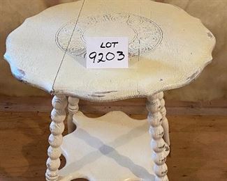 Lot 9203.  $45.00 Antique, shabby chic round table with carved design in the top, with  small lower shelf.  Constructed with 3 pieces of wood that are notched and joined together.  Seams are visible by intent.	24"Diameter  24"T