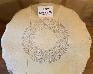 Lot 9203.  $45.00 Antique, shabby chic round table with carved design in the top, with  small lower shelf.  Constructed with 3 pieces of wood that are notched and joined together.  Seams are visible by intent.	24"Diameter  24"T.   Cute top!!