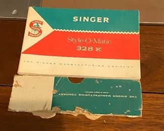 Lot 9210. $165.00 Vintage Singer Model 328K Stylomatic Singer Sewing machine in cabinet.  Includes original metal attachments and some sewing notions and bench seat. 26" W x 17" D 