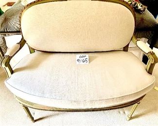 Lot 9168.  $295.00 Upholstered settee with cream colored fabric and green wood finish with gold accent trim.  The upholstered back needs to be secured to the settee. The settee matches the chair from previous lot #9167	42" W x 39" H x 24" D