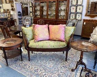 Caned back salon settee with silk cushion, Silk pillows, antique round occasional table, antique tilt top table.