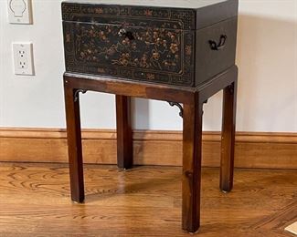 BLACK LACQUERED BOX on STAND | Lacquer decorated box with hinged lid, having a key and side handles, permanently affixed to a four-leg wood stand with carved supports; h. 24 x w. 16 x d. 12 in. 