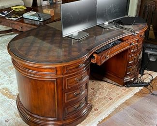 EXECUTIVE'S DESK | Seven Seas by Hooker Furniture, kidney form with a parquetry top, drawer keys and paperwork present, with a conforming protective glass top; h. 31 x w. 77 x d. 41 in. (approx.) 