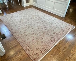 PATTERNED WOOL CARPET | Handmade, having a beige field with an overall pattern of aubergine devices, with a border of red, pink, and purple scrolls and flowers; appearing in overall excellent condition; 12 ft. x 8 ft. 11 in. 