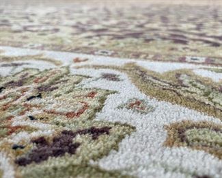 HANDWOVEN PATTERNED CARPET | Purple/brown field with green and beige overall floral pattern, within a beige border of scrolling leaves and blossoms, in very good condition; 12 ft. 6 in. x 8 ft. 11 in. 
