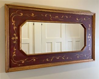 PAINT-DECORATED MIRROR | Folk art style painted panel with scrolling bellflower, with an inset octagonal beveled glass mirror, in excellent condition; 27 x 47 in. 