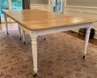 SOLID WOOD DINING TABLE | Having white painted legs on casters, with a wood top and a mechanical extension mechanism; 64 x 49 in. (without leaves); two leaves (ea. 18-1/2 in. wide), table pictured with the two leaves inserted 