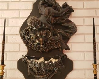 Resin wall fountain with upside down cherub over crest	