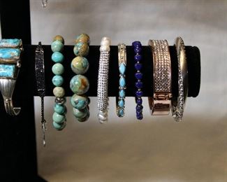 Detail of large assortment of contemporary sterling silver and semi precious gemstone bracelets, bangles, and cuffs including opals, amethysts, pearls, turquoise, black spinels, apatite, and garnets.