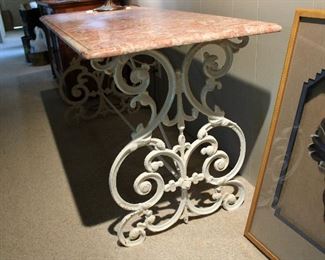 Detail of ornate base on wrought iron base with pink marble top patisserie style table