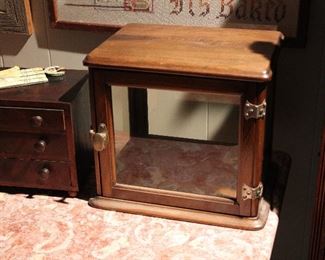 Miniature display cabinet with all glass sides and door next to a 19th c. miniature 3 drawer chest.
