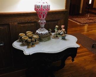 marble top table featuring a cut cranberry lamp 
