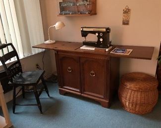 Sewing machine in cabinet, black  painted chair, and covered basket