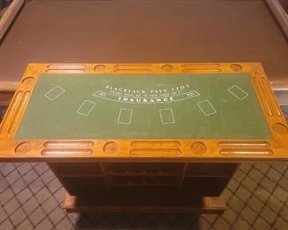 Mid Century Bar with Gambling Levels on Top               Very unique bar/game table with removable tops that start with blackjack and remove to reveal a Roulette wheel with gambling graphics the a craps table.
 