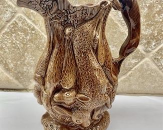 Antique Bennington Hunting Scene Glazed Pitcher 19th century pitcher has the greyhound dog handle and the hanging game birds.  Mottled Deep Brown Glaze with Green and Blue Glaze Bottom.  