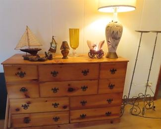 Pine cabinet  4 rows of various size drawers . On the cabinet -large ceramic table lamp, small covered wagon novelty lamp,  tall vase , small glass mosaic lamp,  ship model, pipe holders.   Pair tall iron candle stands  