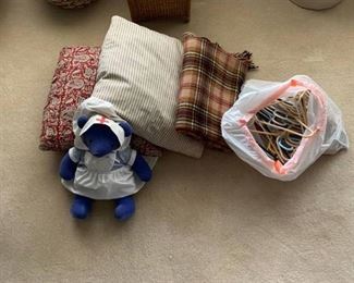 Two pillows, a blanket, stuffed bear and a bag of hangers