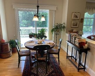 Antique oak round pedestal table; set of 4 newer green stained chairs w/rattan seats; painted harvest table with flip up top;  Cookbooks,  (Plant stands, NFS),  & plants (large pantry boxes & rug, NFS).