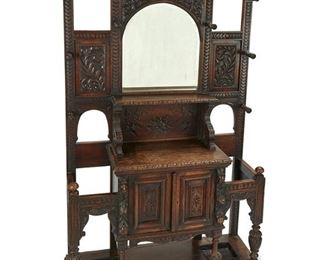 1040
An English Carved Oak Hall Tree
Late 19th/early 20th Century
The oak hall tree with all-over carved floral and scrolling foliate motifs centering a beveled mirror surrounded by hat/coat pegs over a two-door cabinet flanked by umbrella racks
82" H x 48" W x 18" D
Estimate: $800 - $1,200