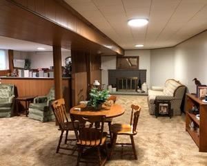 A welcoming view of this lovely home's lower level.  This Hard Rock Maple table and chairs is in Like New Condition and is an excellent size for many areas.  A great design!  Also, the 2 green velvet chairs are in good condition and the bookcase offers great storage potential.  Couch is in very good condition, comfy and ready to go home with you!