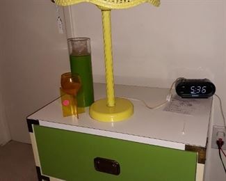 Nightstand with yellow lamp and vintage candles.