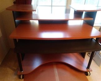 Multi-level wooden office desk.  The black shelf pulls out.