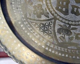 large engraved brass platter on wooden stand (detail)
