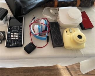 Instax Polaroid camera with Leah rear case, TI calculator, mini jawbone wireless speaker, airbuds, Nintendo DS lite, Beats headphones 