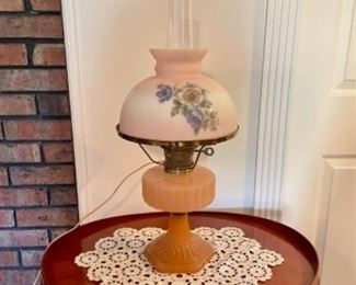 Pink Aladdin Corinthian lamp shown with chimney and hand painted shade. Mahogany lamp table