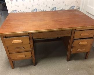 large oak desk that has six pull out drawers and the pull out writing tables on each side also. It does have the center pull out drawer also